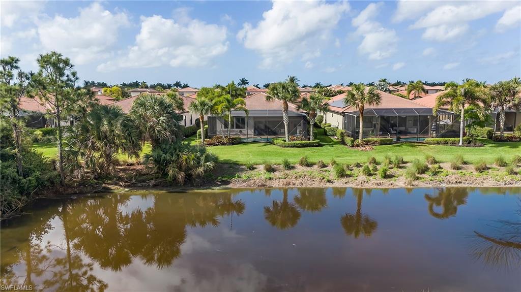 1287 Manado Drive Naples, FL 34113 - Photo 24 of 32 a front view of a house with a garden and lake view