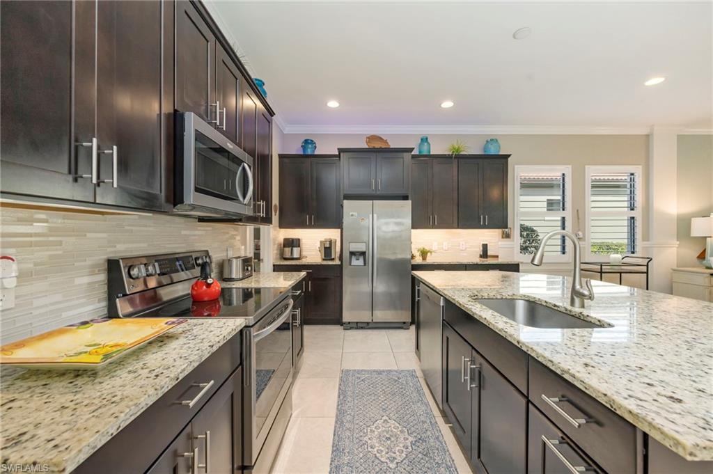 1287 Manado Drive Naples, FL 34113 - Photo 9 of 32 a kitchen with stainless steel appliances granite countertop a sink stove and refrigerator