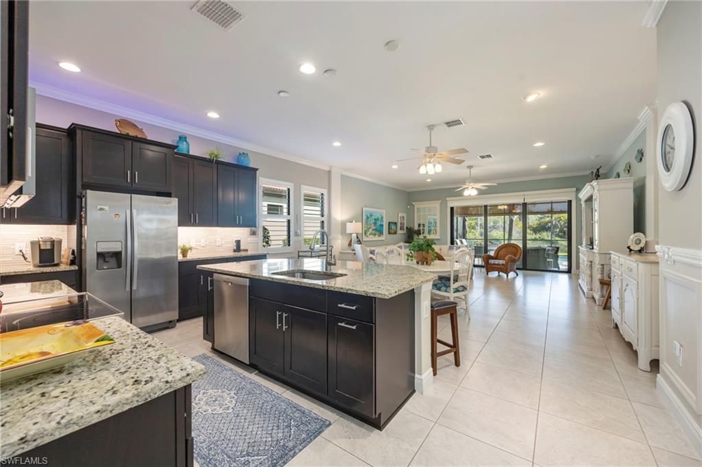 1287 Manado Drive Naples, FL 34113 - Photo 10 of 32 a kitchen with stainless steel appliances granite countertop a sink stove and refrigerator