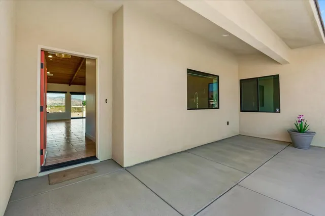 an empty room that has a mirror and potted plant