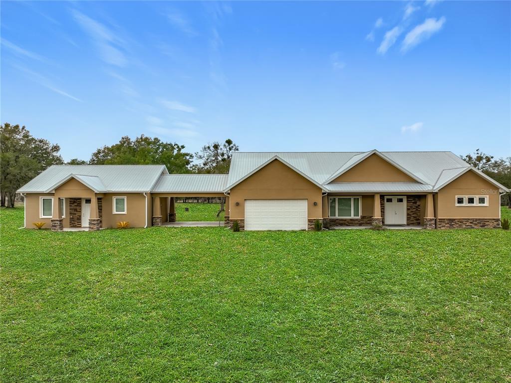 a view of a big house with a big yard and large trees