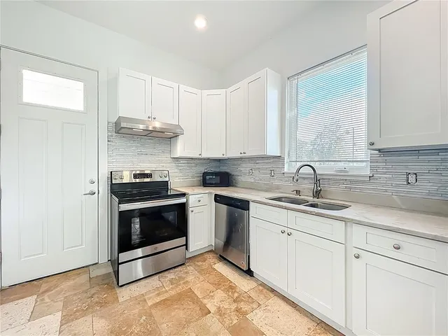 a kitchen with a sink a stove cabinets and a window