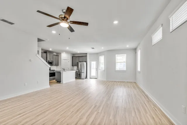 a view of empty room with wooden floor and fan