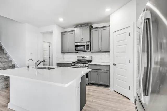 a kitchen with granite countertop a sink a stove top oven a refrigerator cabinets and a window