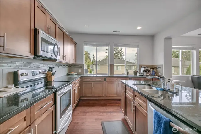 a kitchen with kitchen island granite countertop a sink stove and cabinets