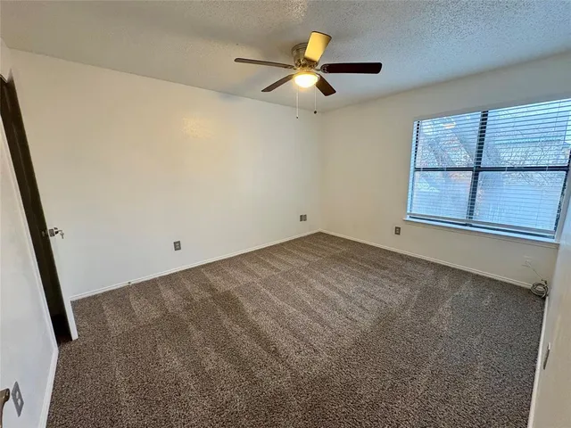 an empty room with a ceiling fan and window