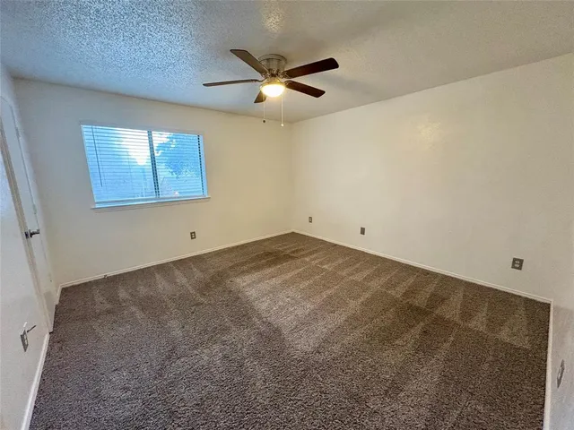 an empty room with a ceiling fan and window