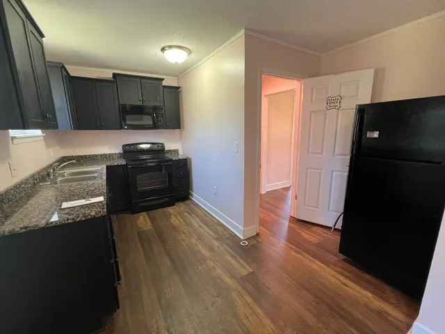 a kitchen with granite countertop a refrigerator and a sink