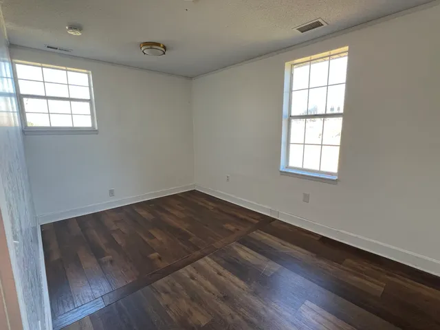 an empty room with wooden floor and windows