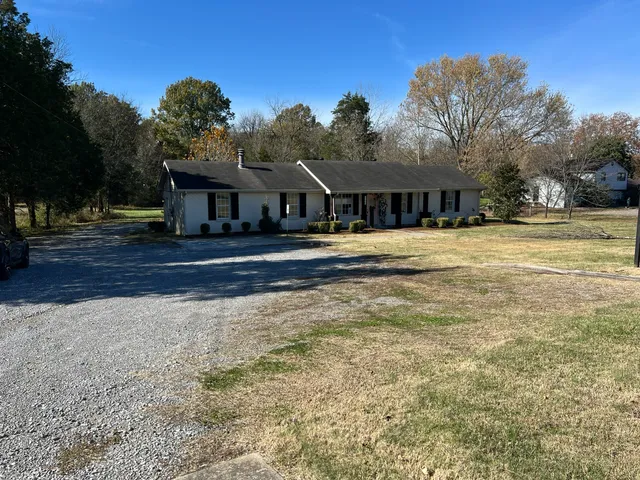 a front view of house with yard and trees in the background