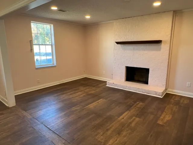 an empty room with wooden floor and fireplace