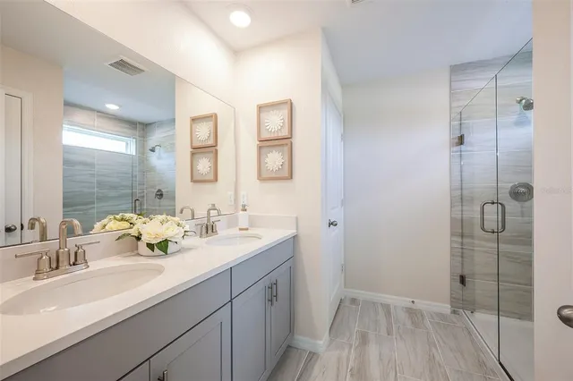 a bathroom with a double vanity sink mirror and shower