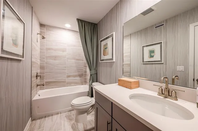 a bathroom with a bathtub shower sink vanity mirror and toilet