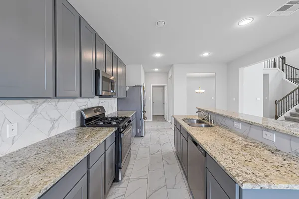 a kitchen with granite countertop stainless steel appliances a sink stove top oven and cabinets