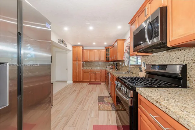 a kitchen with stainless steel appliances granite countertop a refrigerator a stove and a wooden floors