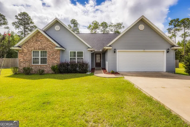 a front view of house with yard and trees in the background