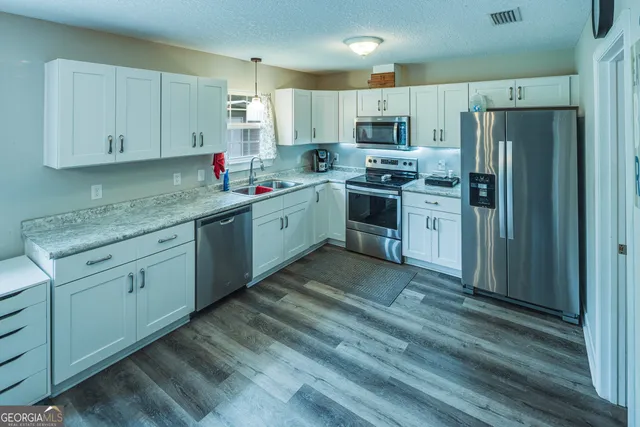 a kitchen with granite countertop cabinets stainless steel appliances a sink and a window