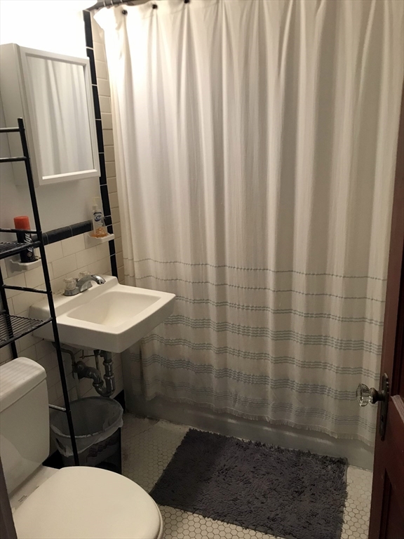 393 West Street, Unit 2 Walpole, MA 02081 - Photo 14 of 21 a bathroom with a sink a toilet a mirror and shower curtain