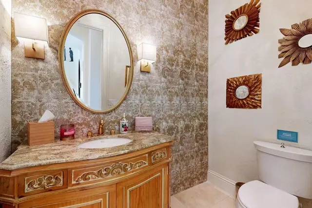 a bathroom with a granite countertop toilet a sink and a mirror