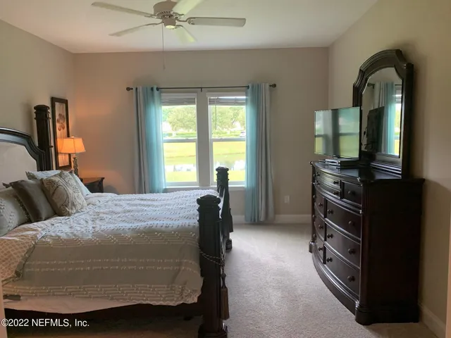 a bedroom with a bed and a flat tv screen on dresser