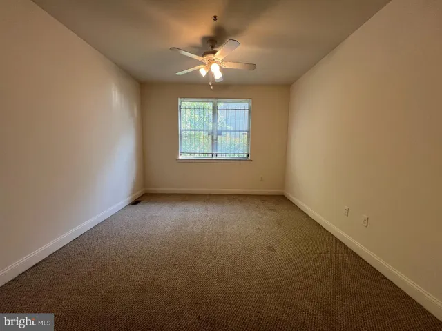 an empty room with a chandelier fan and windows