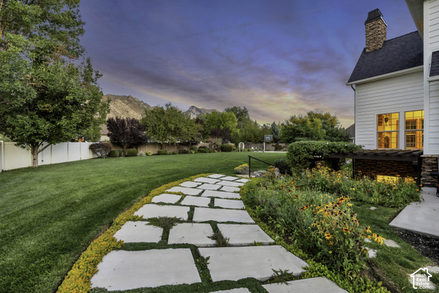 259 Twin River Loop Alpine, UT 84004 - Photo 51 of 61 Expansive green lawn, stone paver pathway, mature trees, established garden beds, and mountain backdrop