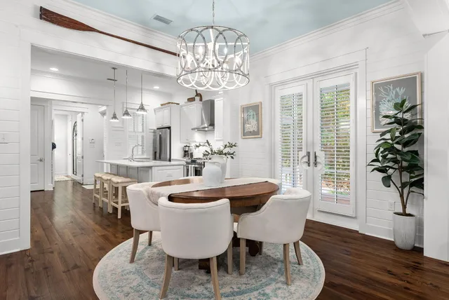 a dining room with wooden floor a chandelier a wooden table and chairs