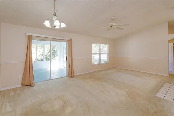 an empty room with chandelier fan and windows