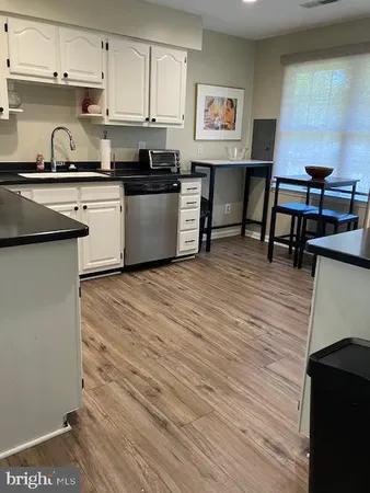 a kitchen with stainless steel appliances granite countertop a stove top oven a sink dishwasher and cabinets with wooden floor