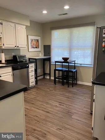 a view of a kitchen with kitchen island a counter top space a sink a stove and wooden floor