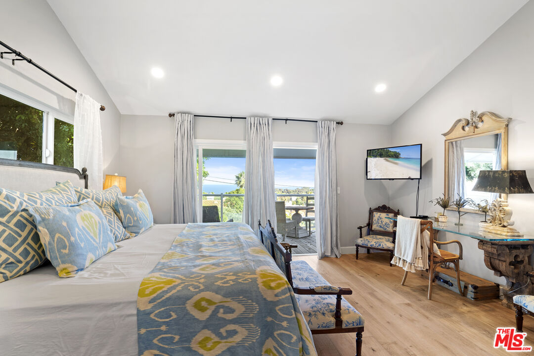 6363 Zumirez Drive Malibu, CA 90265 - Photo 14 of 34 a spacious bedroom with a bed a table and chair