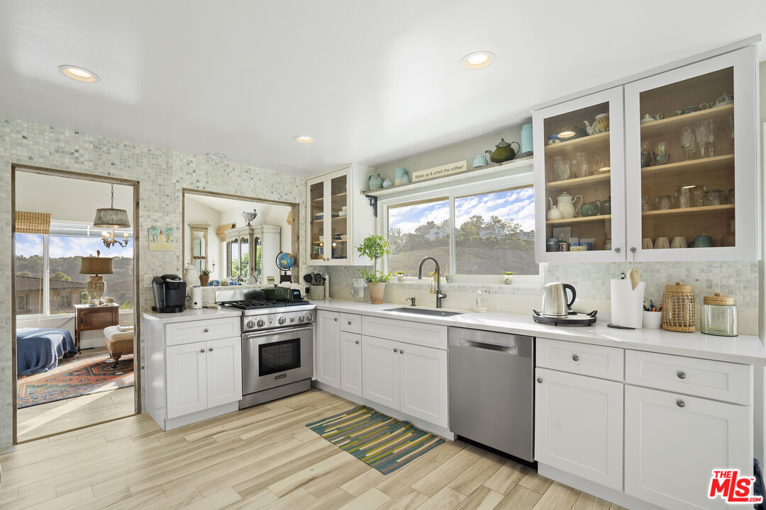 6363 Zumirez Drive Malibu, CA 90265 - Photo 9 of 34 a large white kitchen with a sink and cabinets