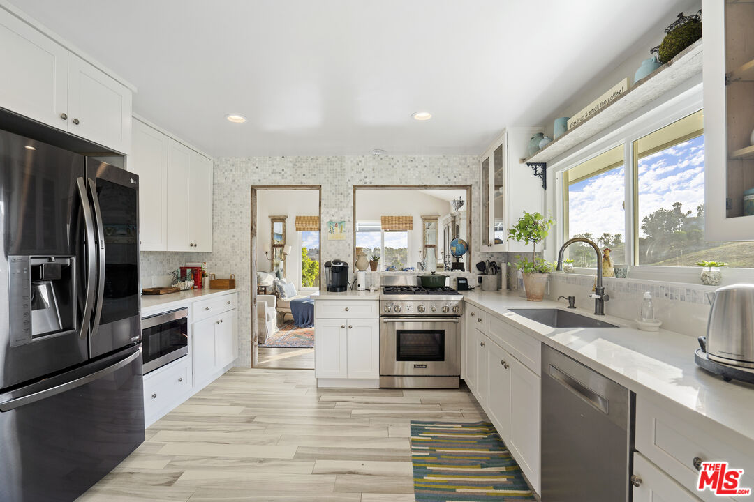 6363 Zumirez Drive Malibu, CA 90265 - Photo 10 of 34 a large kitchen with stainless steel appliances sink a microwave and cabinets
