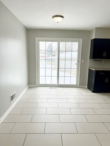 a view of an empty room with a window and a kitchen