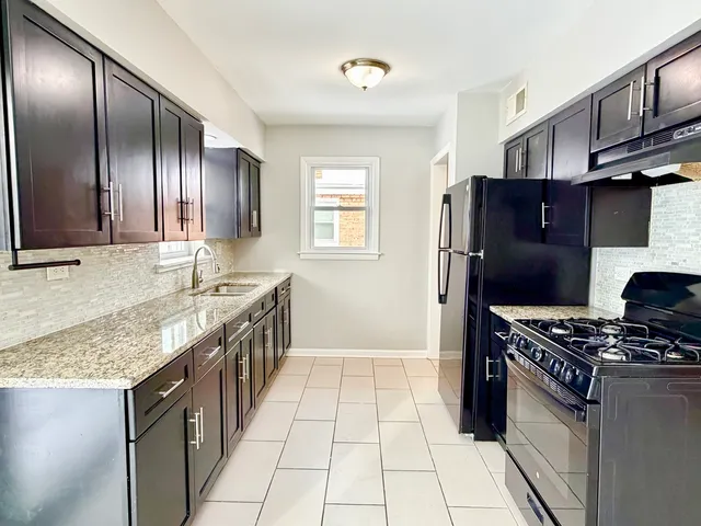 a kitchen with stainless steel appliances granite countertop a stove a refrigerator and a sink