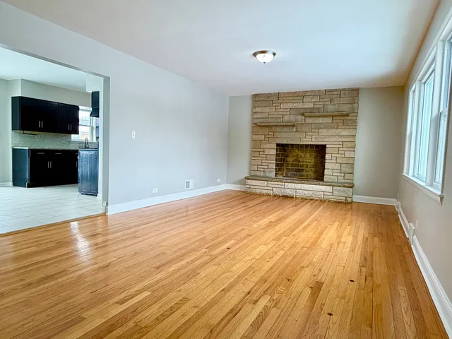 an empty room with wooden floor fireplace and windows