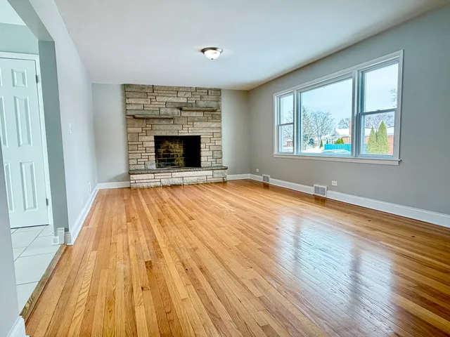 a view of empty room with wooden floor and fireplace