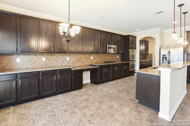 a kitchen with stainless steel appliances granite countertop a stove a sink and a refrigerator