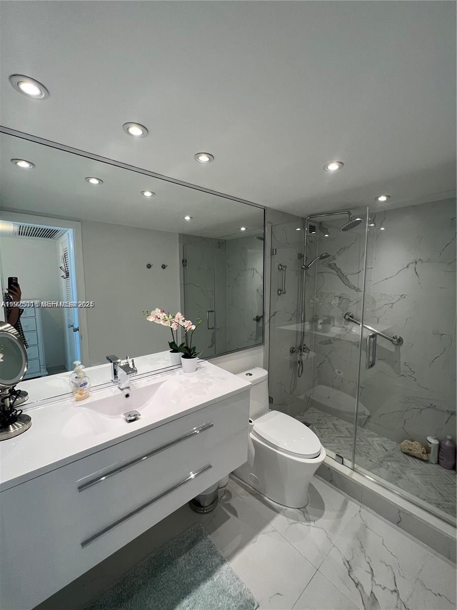 5555 Collins Avenue, Unit 7T Miami Beach, FL 33140 - Photo 14 of 19 a bathroom with a double vanity sink toilet and shower