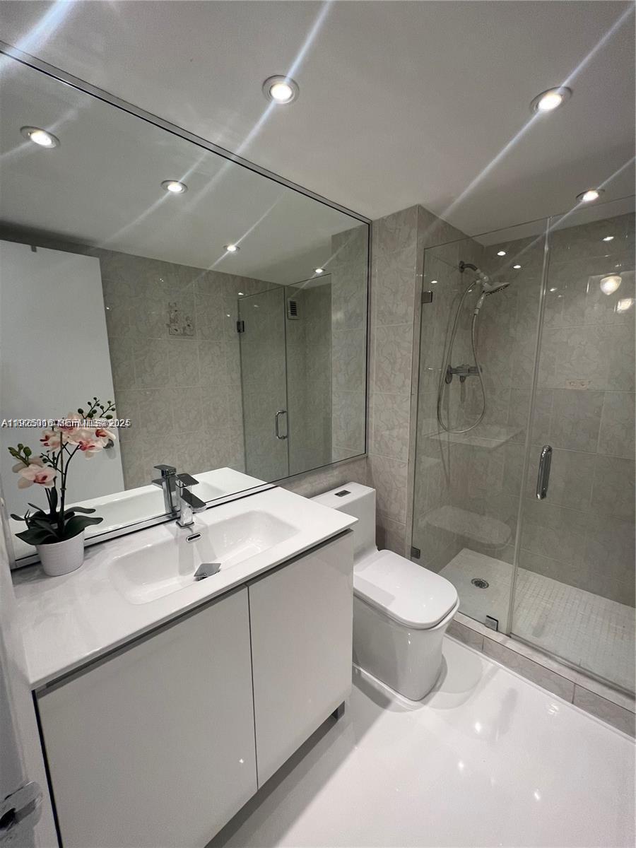 5555 Collins Avenue, Unit 7T Miami Beach, FL 33140 - Photo 17 of 19 a bathroom with a double vanity sink toilet and shower