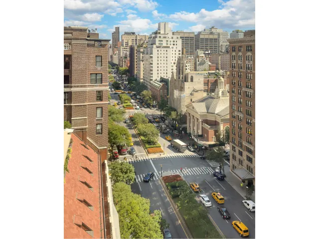 a front view of a building with lot of cars and trees