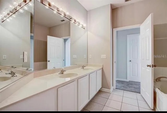 a spacious bathroom with a double vanity sink a mirror and a shower