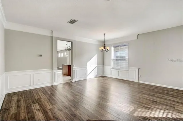 a view of empty room with wooden floor and window