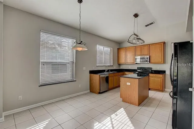 a kitchen with stainless steel appliances granite countertop a stove a sink dishwasher a refrigerator and a window