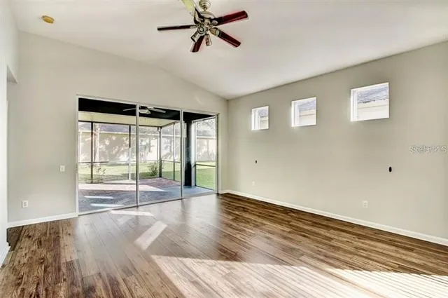 a view of empty room with wooden floor and fan