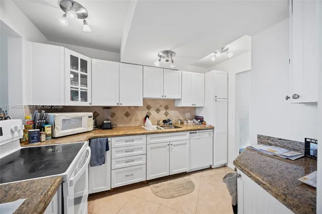 a kitchen with granite countertop a sink a stove and cabinets