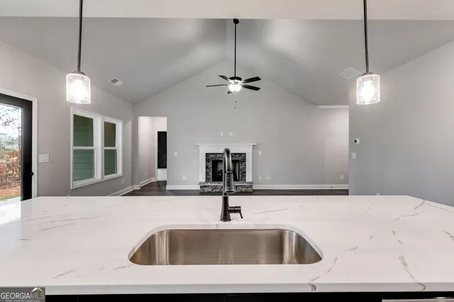 a kitchen with a sink a center island a chandelier and living room view