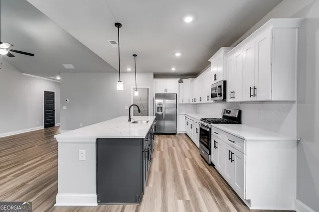 a large kitchen with stainless steel appliances kitchen island a stove a sink dishwasher and a refrigerator with wooden floor