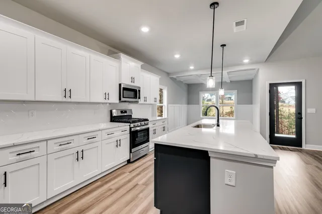 a kitchen with kitchen island granite countertop a stove a sink a center island and cabinets