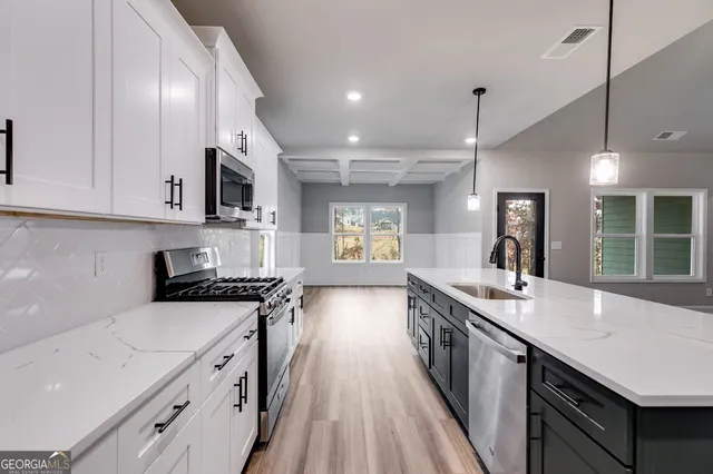 a kitchen with granite countertop a stove top oven a sink a counter space and cabinets